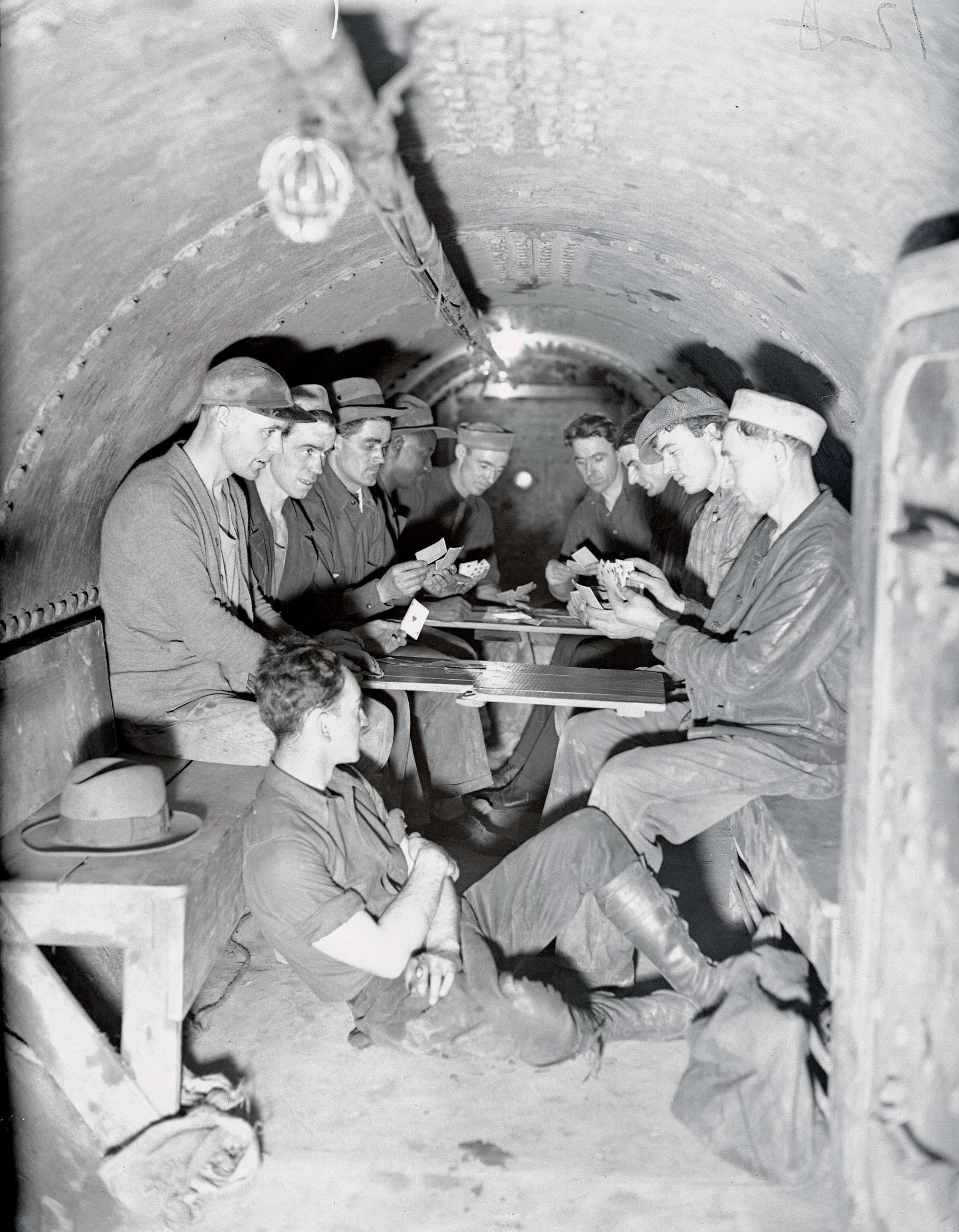 Portraits of subway workers playing cards in a cramped cylindrical chamber
