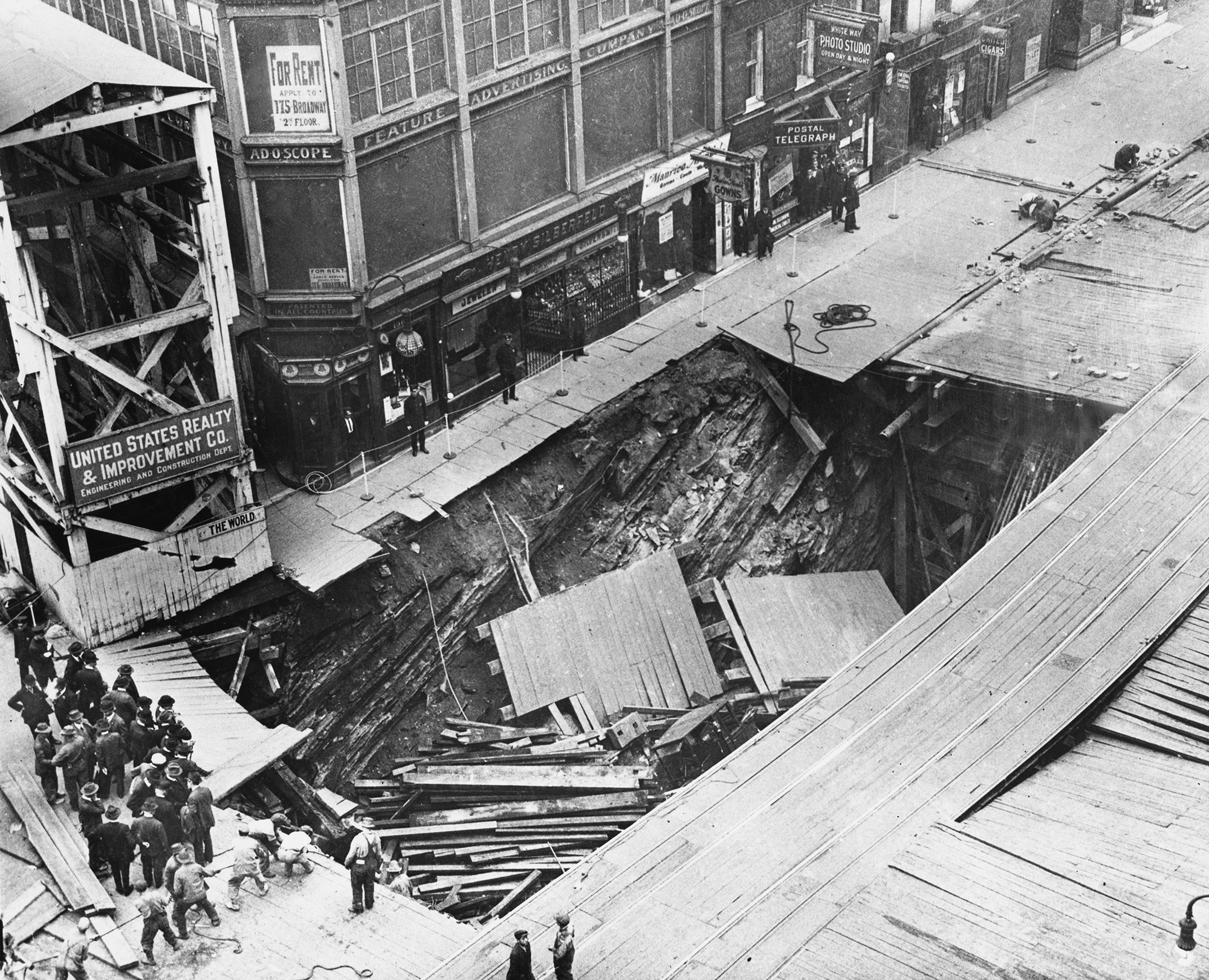 A partial collapse on a street covered in wooden planks shows the underground construction