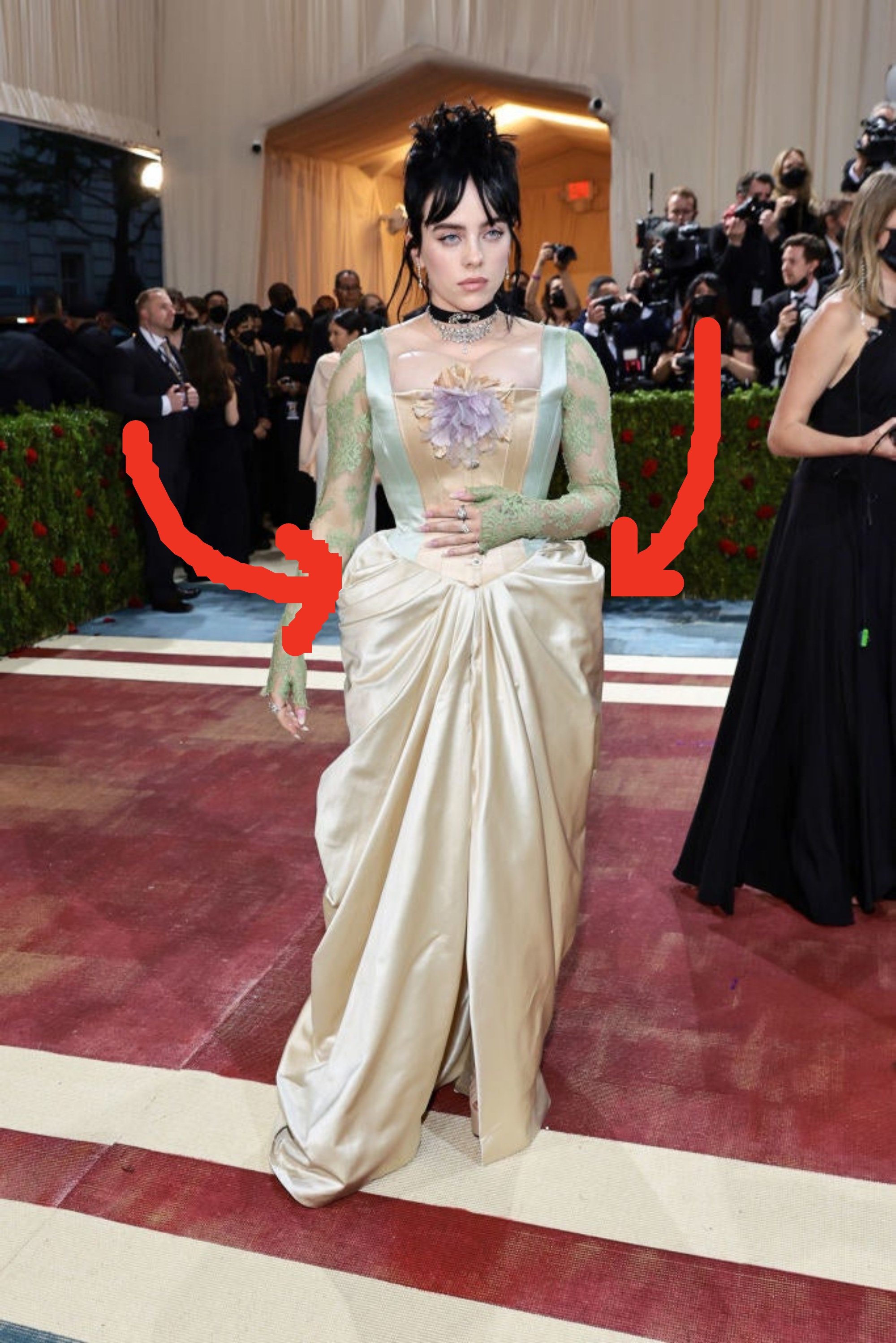 Arrows point out the bustle she&#x27;s wearing, which causes the bottom of her dress to extend backward