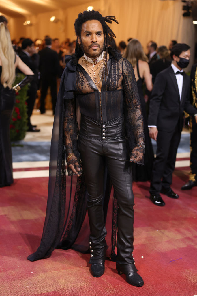 Lenny Kravitz smiling and wearing leather pants and a sheer mesh top