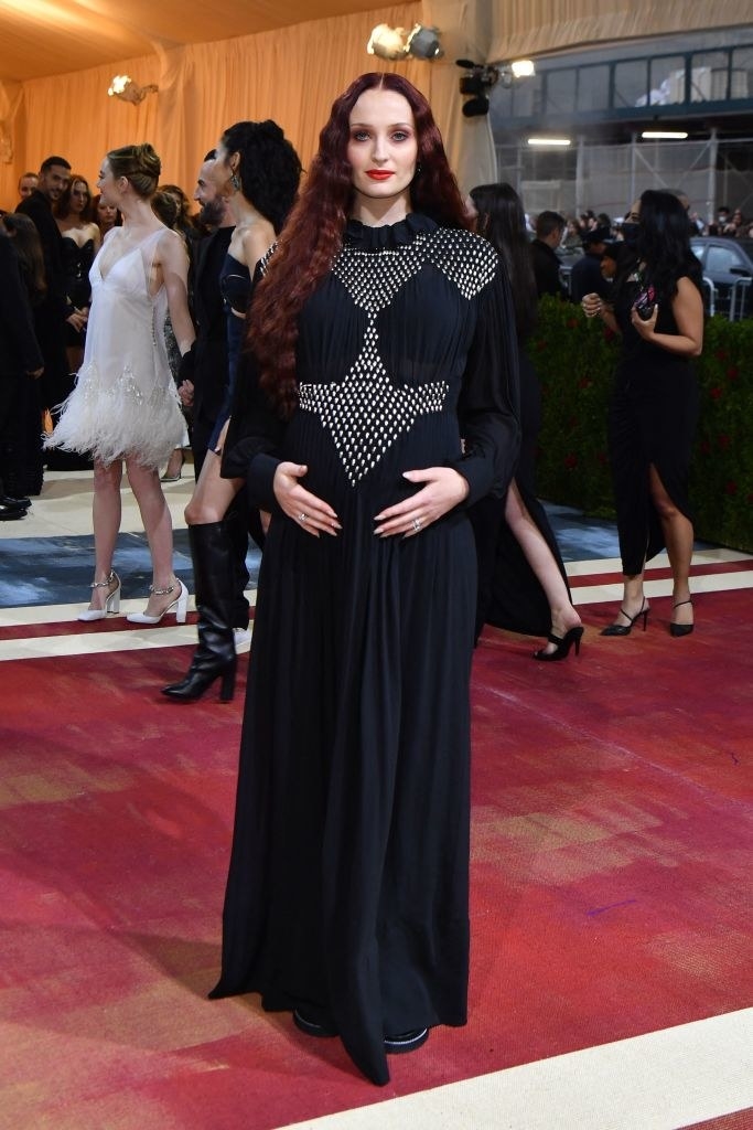 Sophie Turner holding her belly on the red carpet
