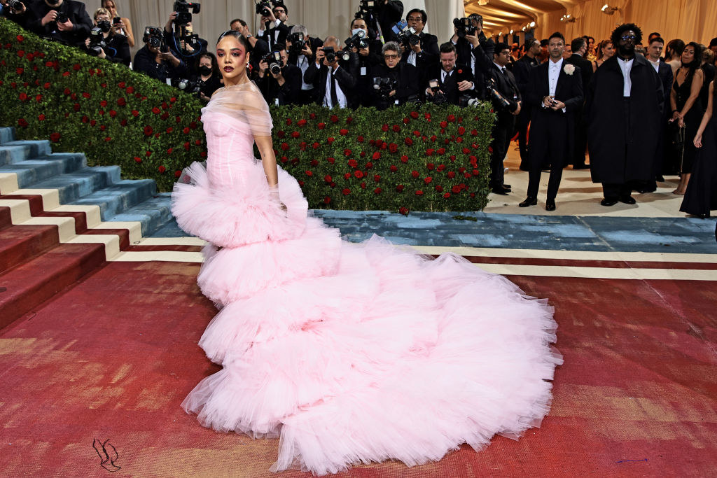 Tessa Thompson in the gown standing on the red carpet as paparazzi look on