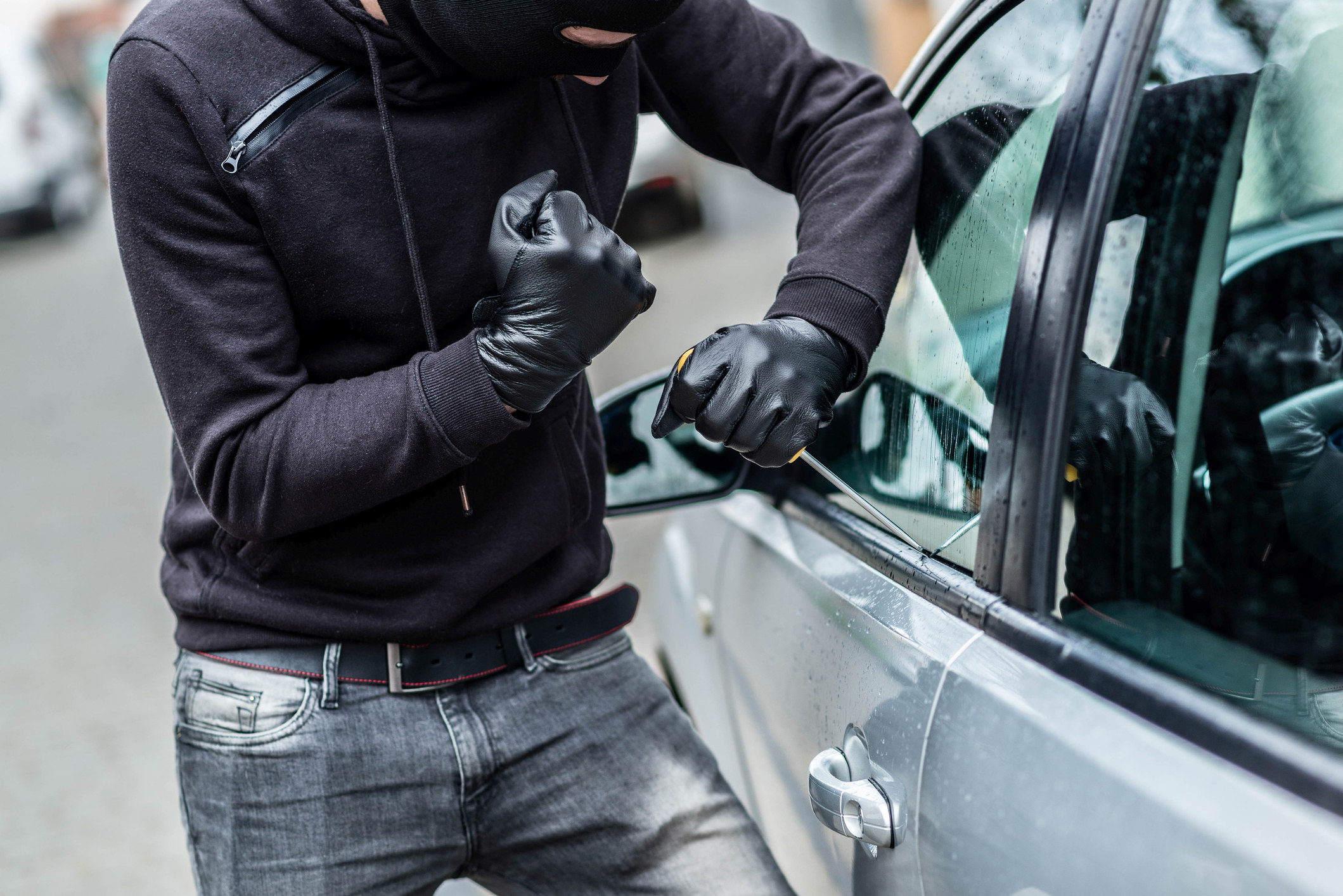 A man breaking into a car.