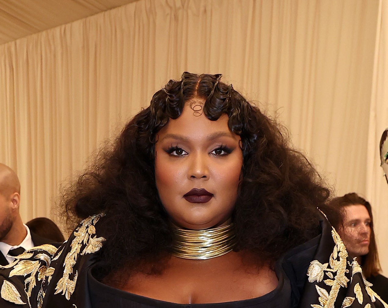 Lizzo wearing a gold choker, dark lipstick, and a &#x27;20s-inspired hairdo