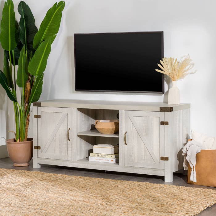 An image of a stone grey farmhouse TV stand with two cabinets and open and closed shelving space