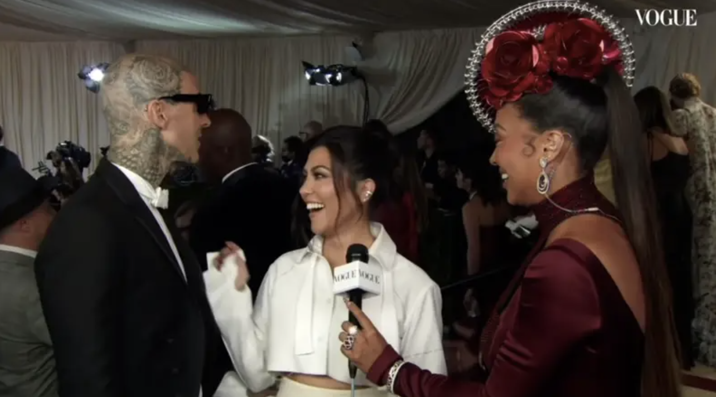 Kourtney laughing and looking back at Travis while being interviewed