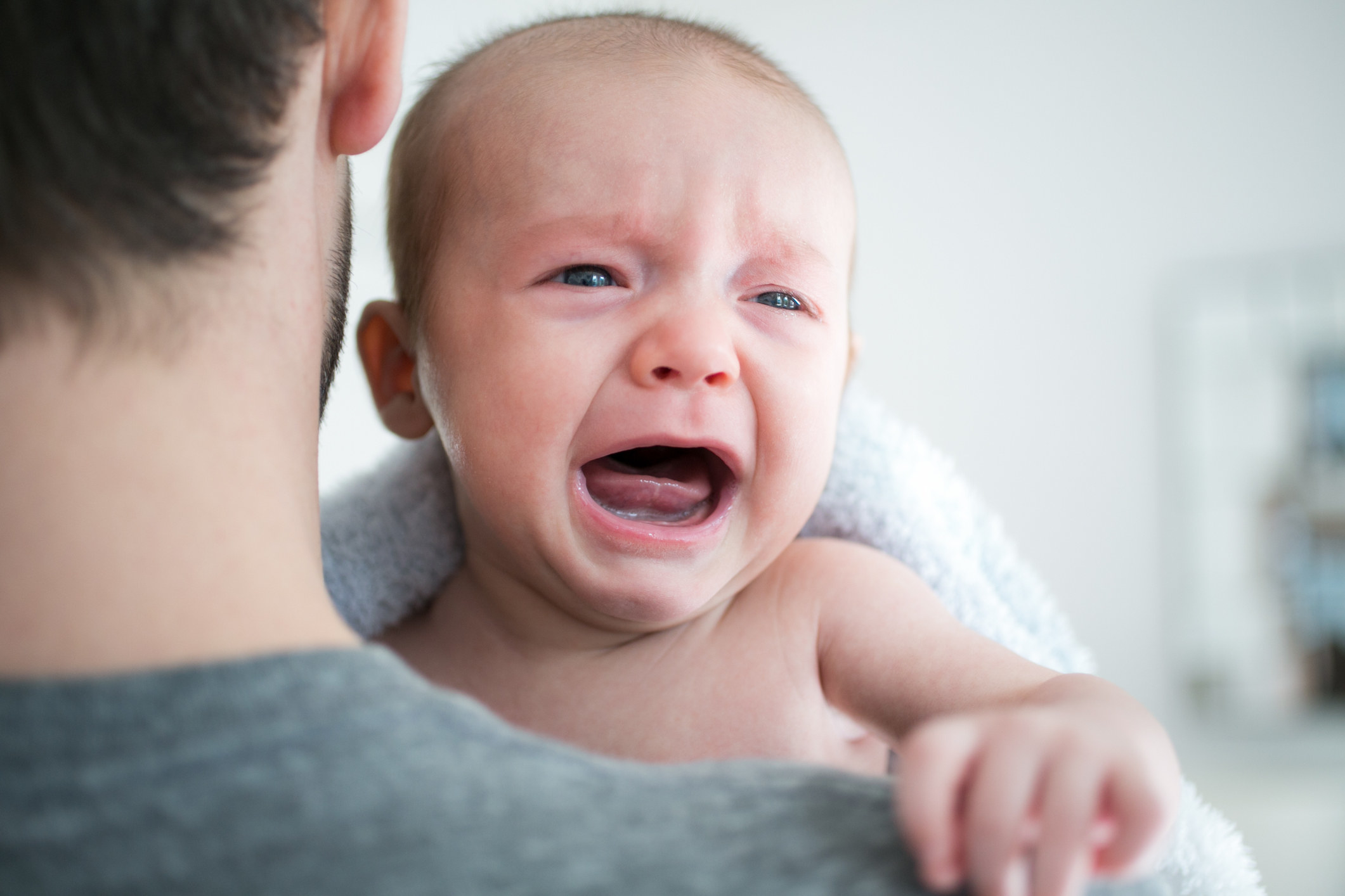 A man holds a crying baby.