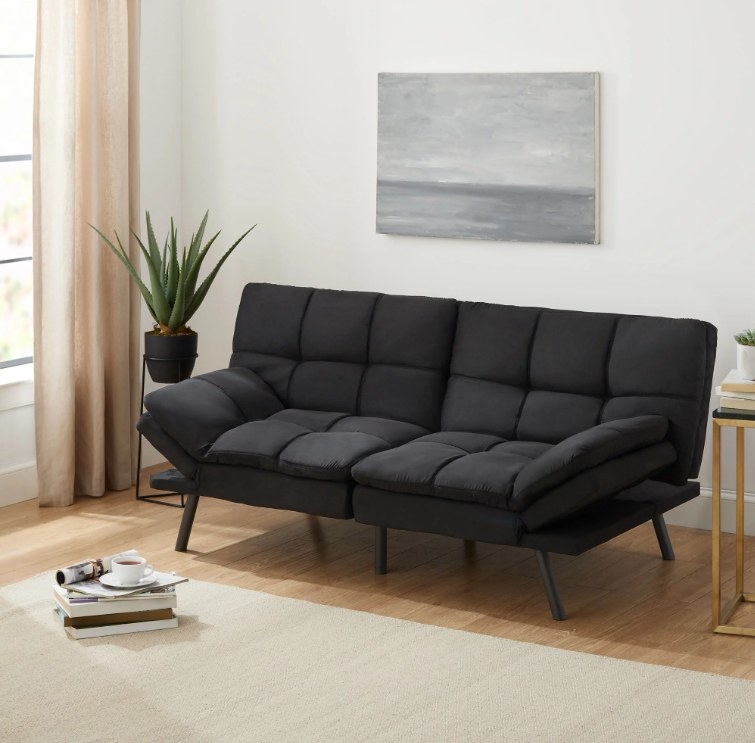 An image of a black memory foam futon with a foldable winged armrest, metal legs, and a sturdy wooden frame