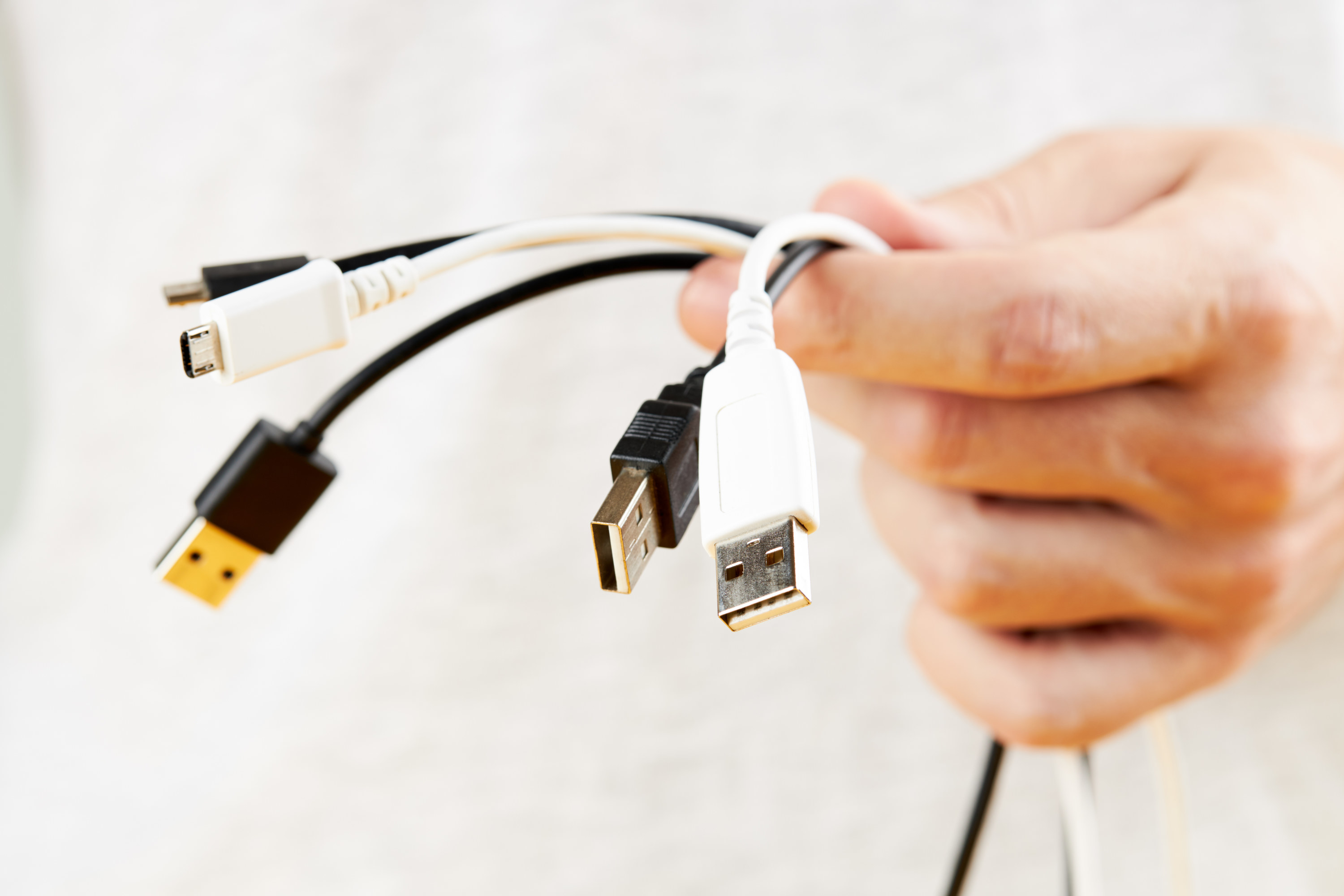 A hand holding multiple phone chargers