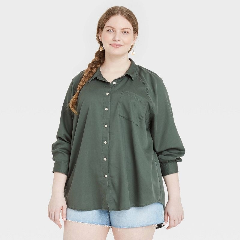 The model wears a green button-up shirt with jean shorts
