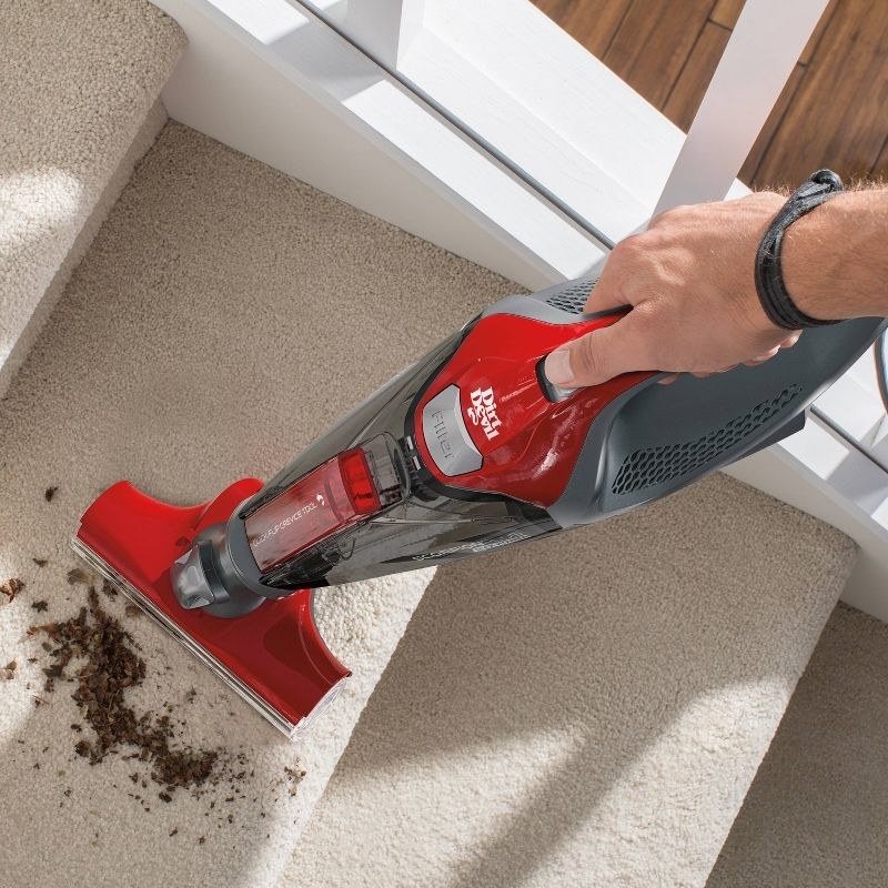 the red vacuum being used on carpeted stairs
