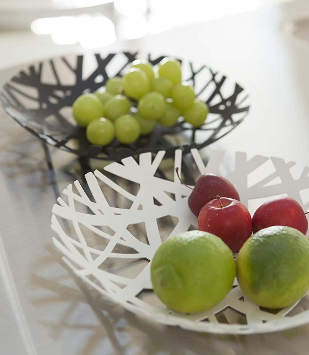 a pair of powder coated steel bowls filled with apples, limes, and grapes