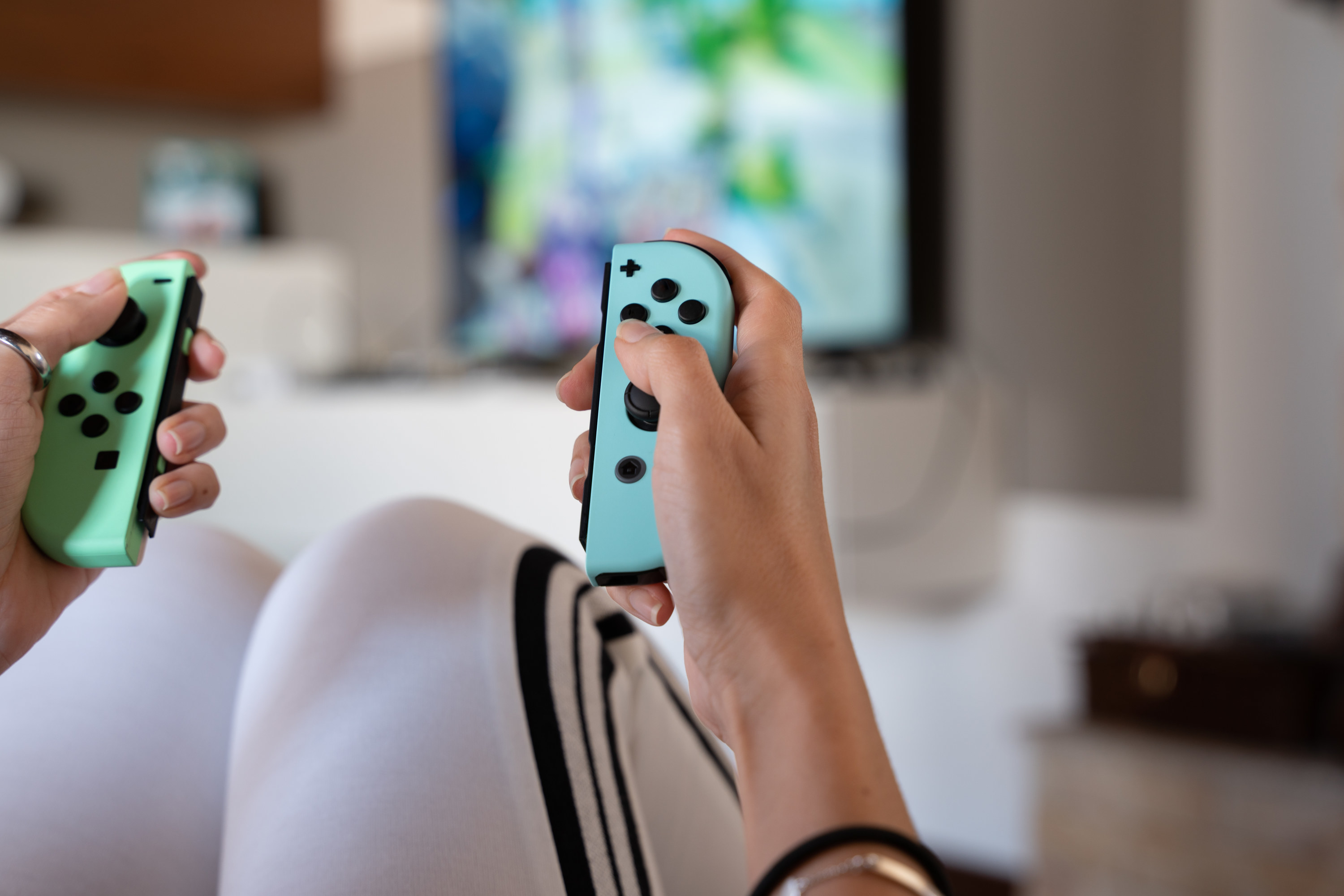 A person&#x27;s hands playing with Nintendo Switch controllers