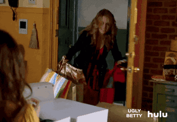 Amanda from ugly betty rushing in the door with arms full of shopping bags