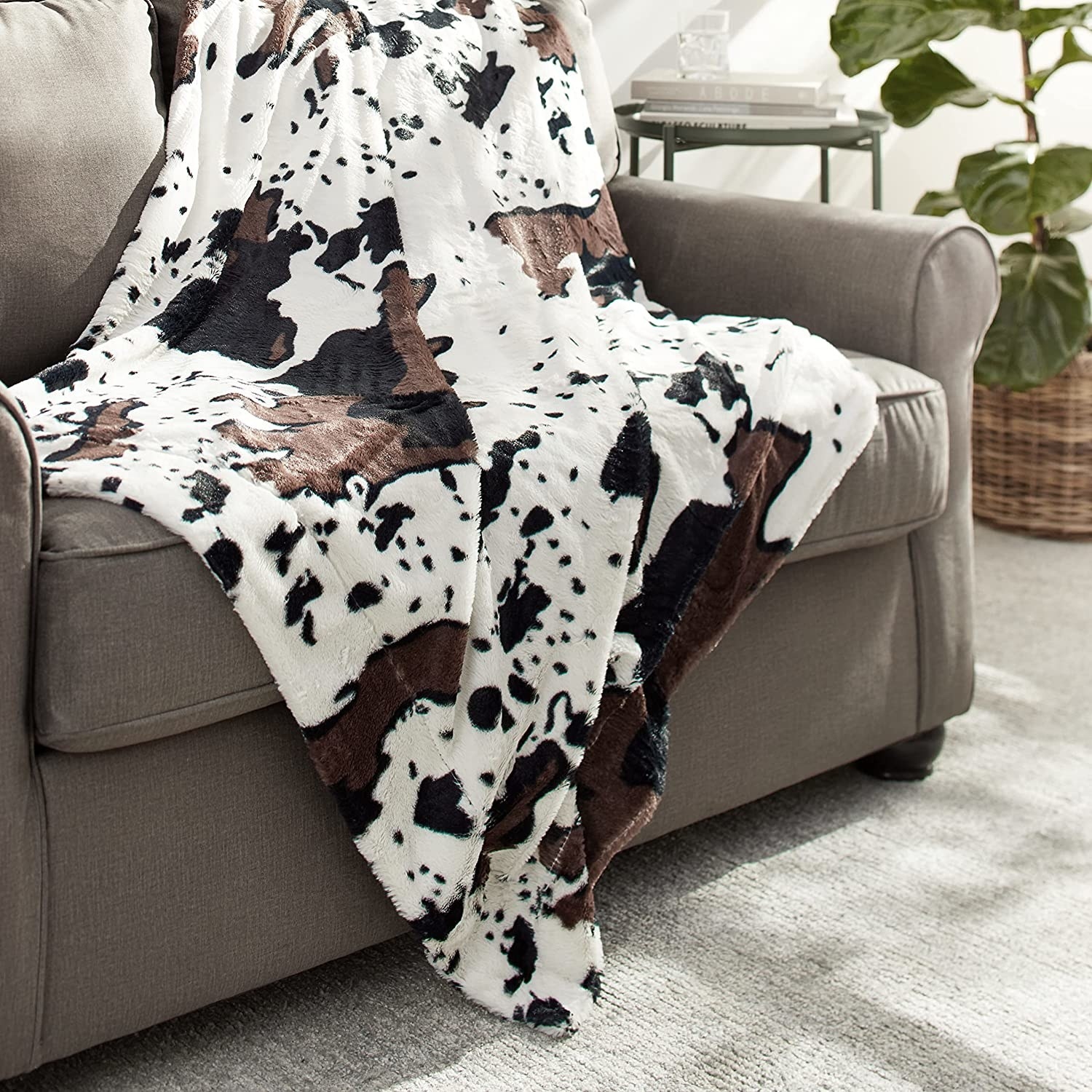a cow print blanket slung onto the arm of a sofa