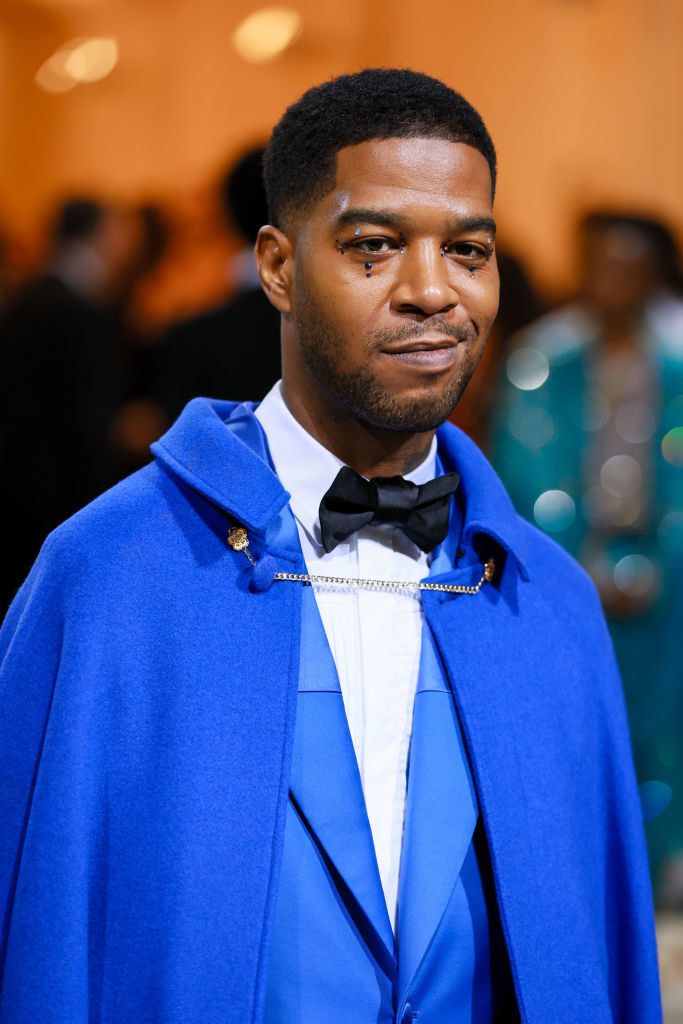 Kid Cudi smiling and wearing a bright blue tux and cape