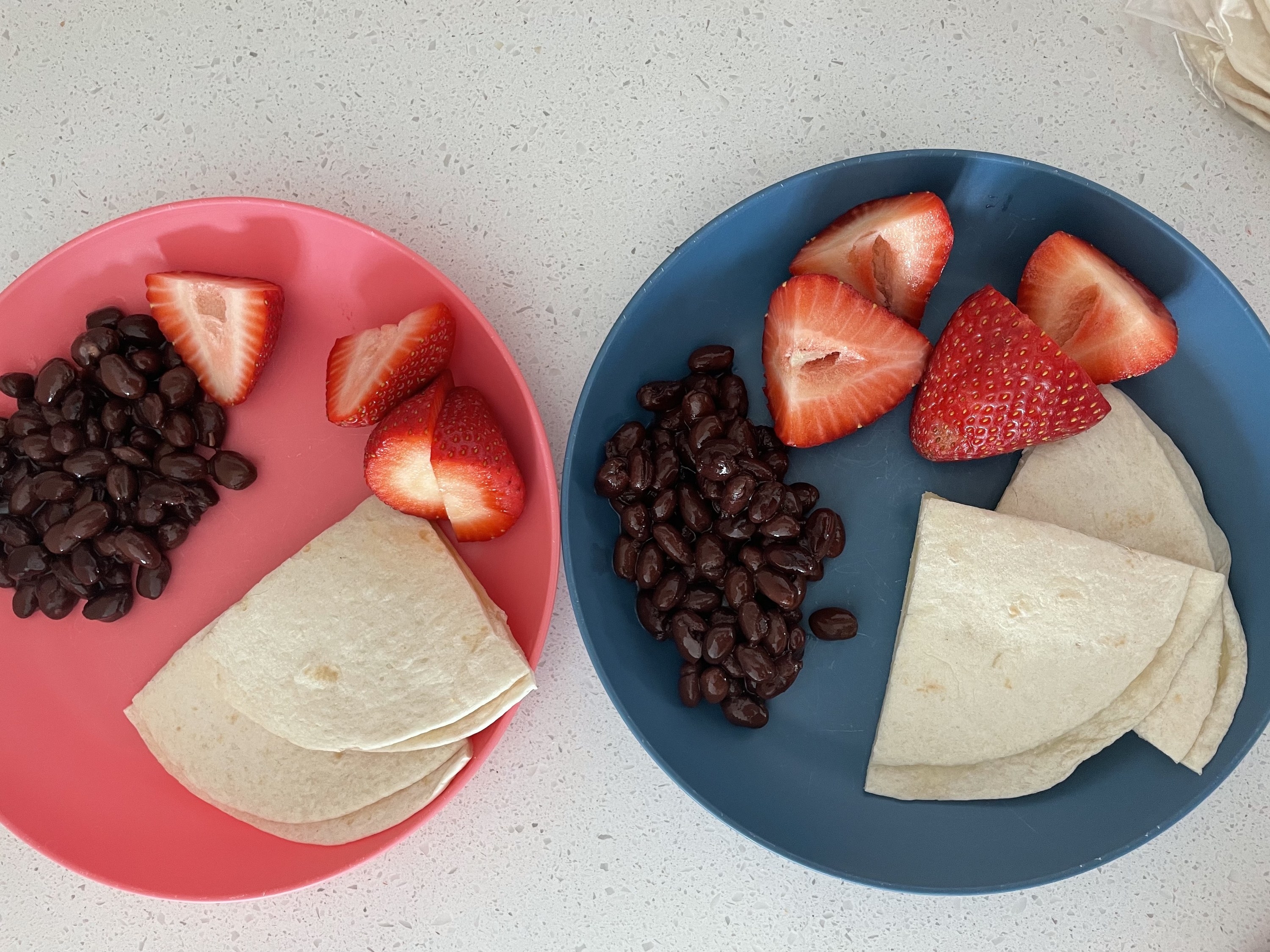 plates with quesadillas, strawberries, and black beans