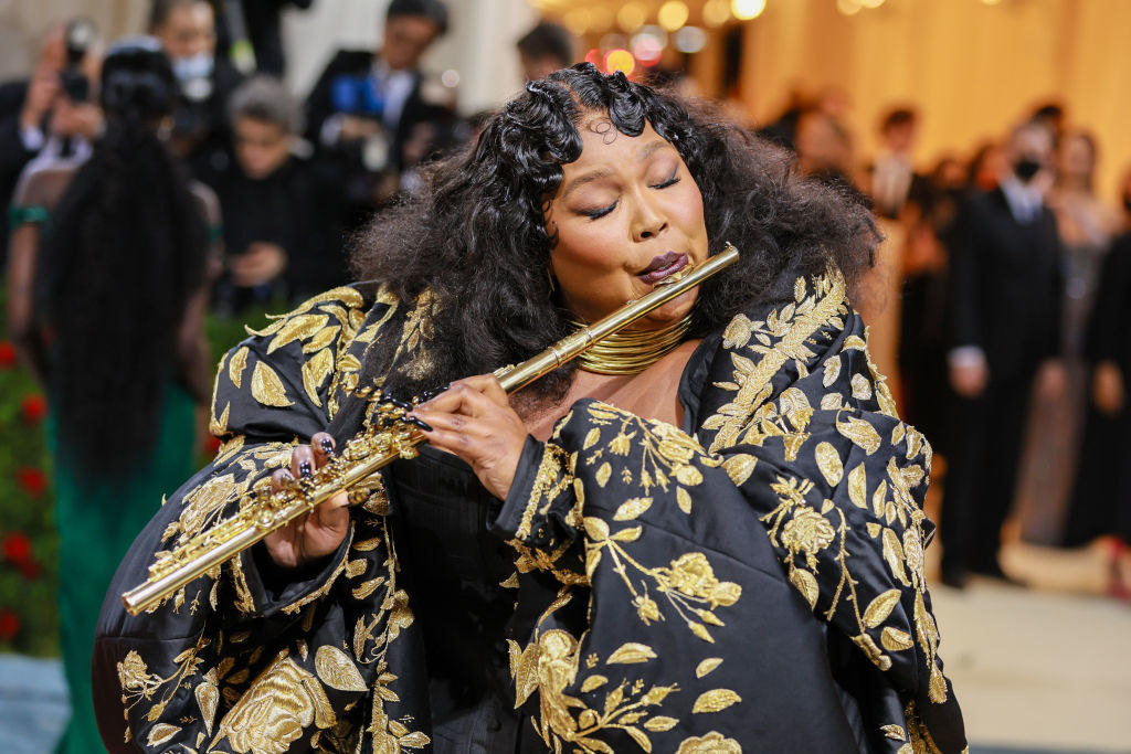 Lizzo wearing the dress and playing a gold flute
