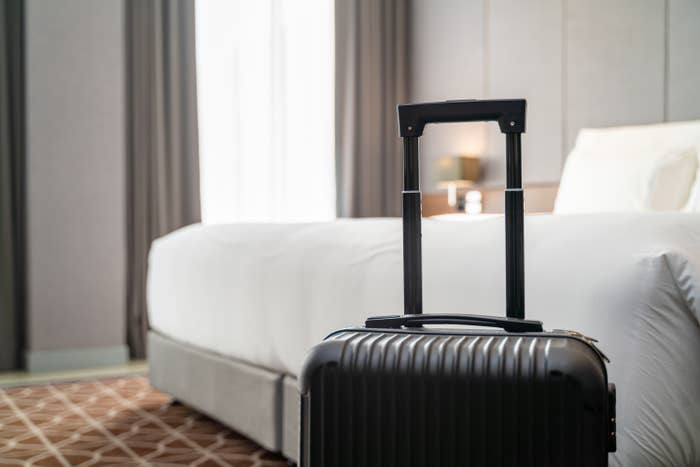 A suitcase in front of a bed in a hotel room