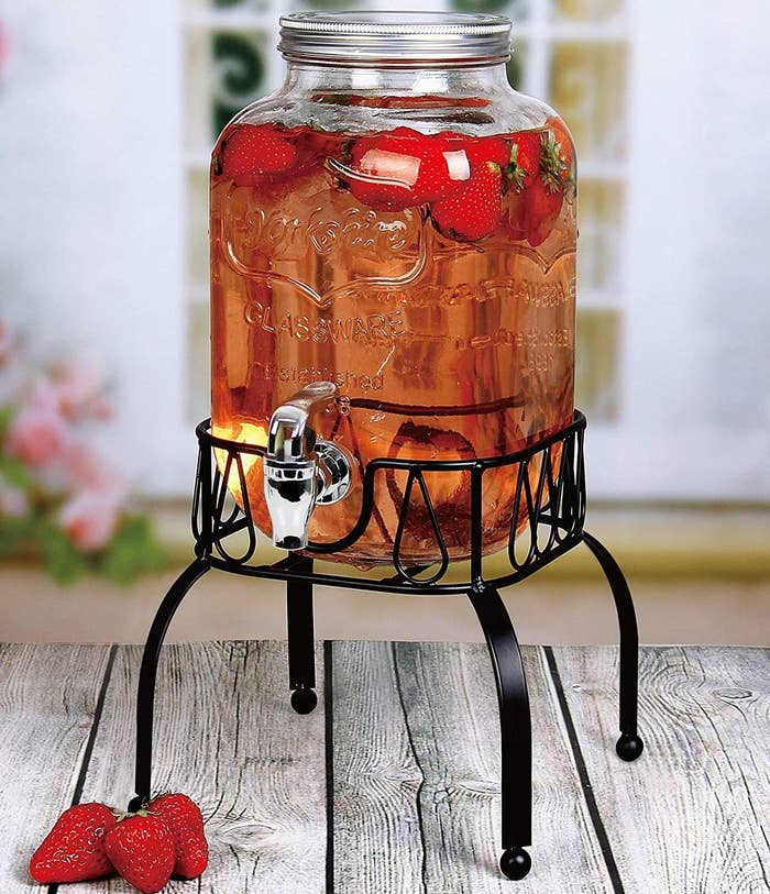 The drink dispenser on a wooden table outside filled with iced tea