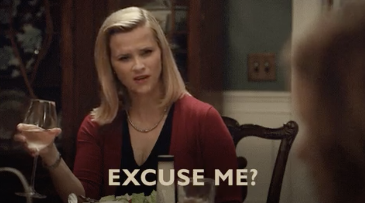 Reese Witherspoon at a dinner table with the words, &quot;Excuse me?&quot;