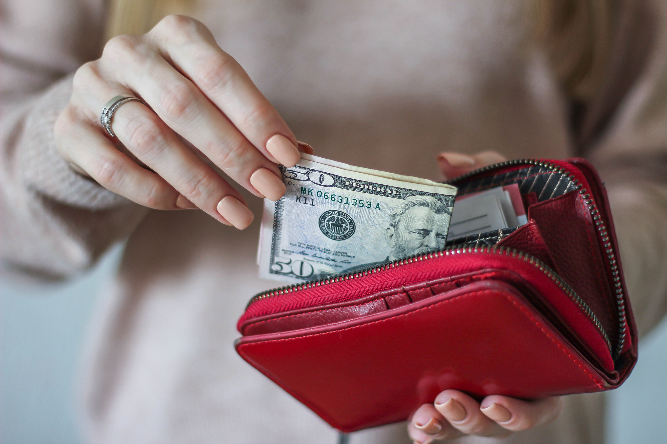 A woman pulling a $50 bill out of her wallet.
