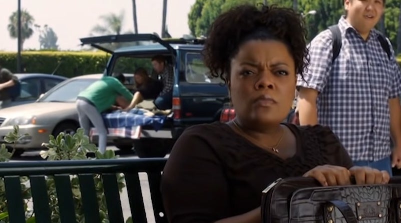 雪莉坐在长椅上Abed提供一个婴儿在一辆SUV在后台的“Community"