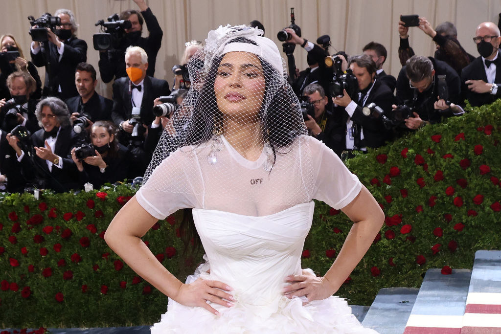 Kylie in a wedding dress and a backward baseball cap with a veil