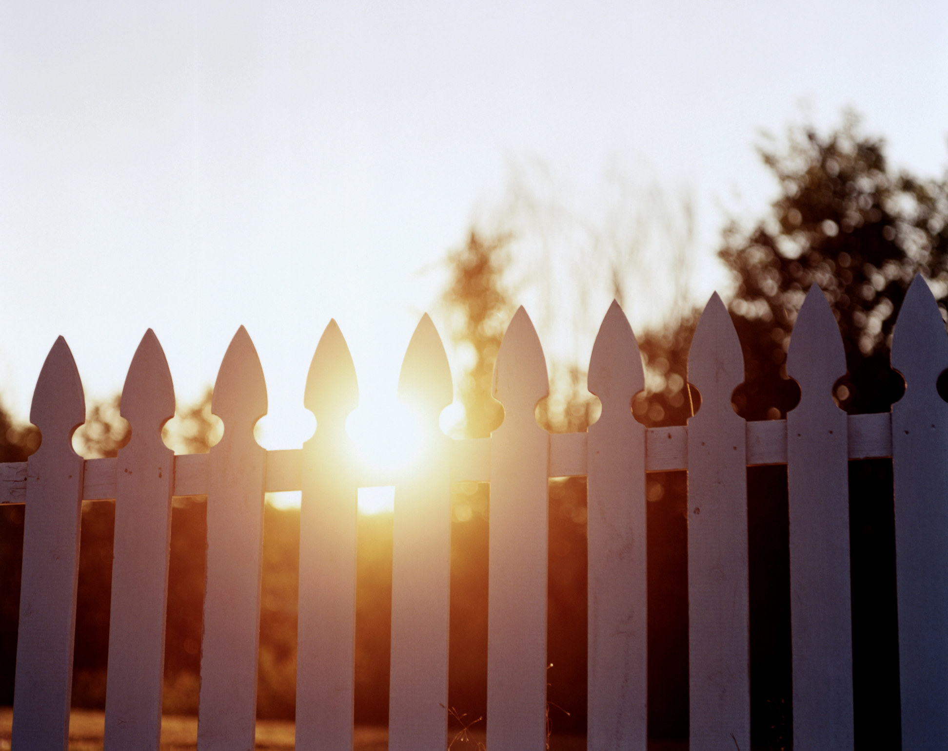 A gated fence with the sun shining through