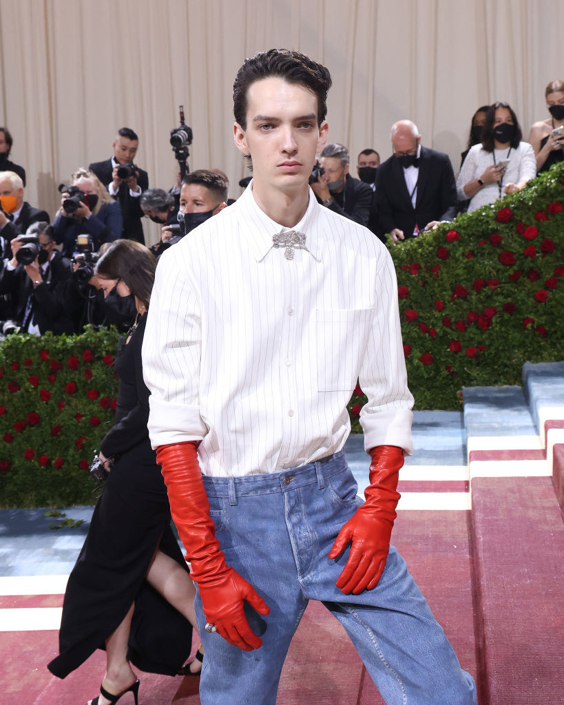 Kodi wears jeans, a button-up shirt, and long red work gloves
