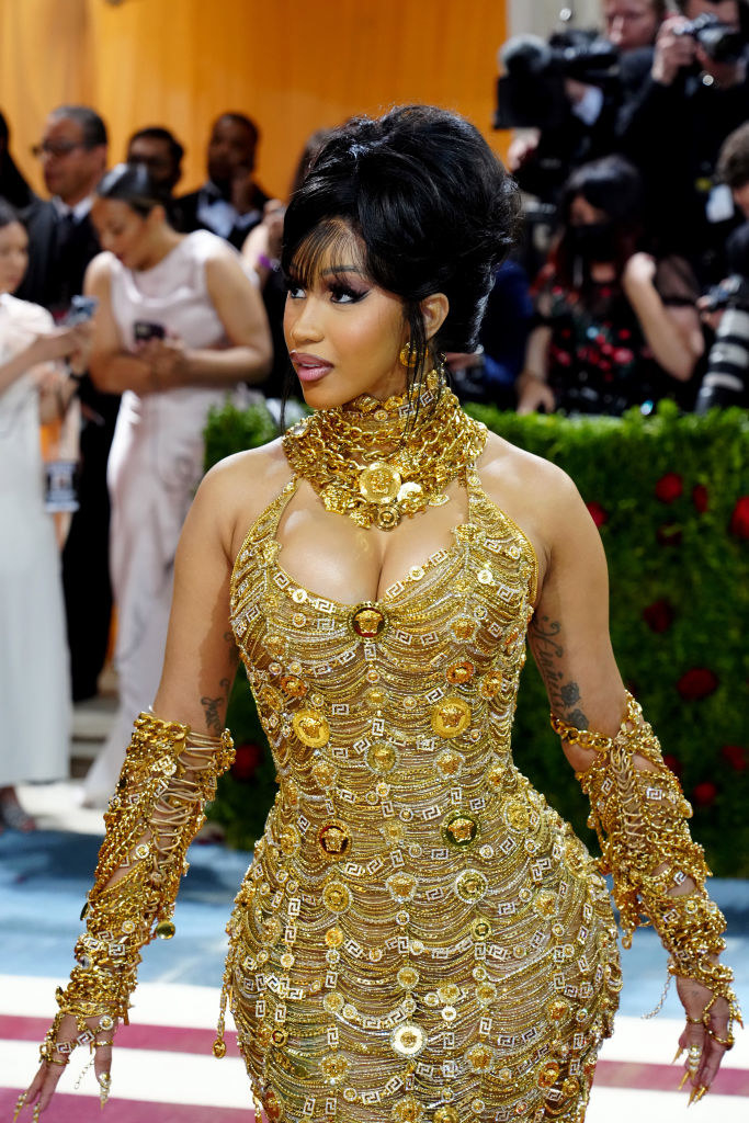 Cardi in a gold and shiny fitted dress