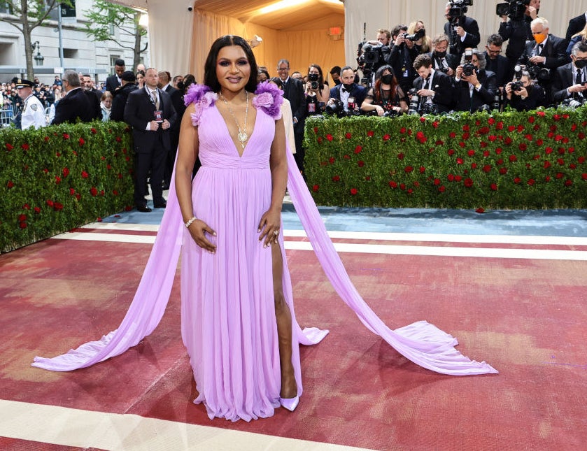 Mindy in a long, lilac dress with big flower accents on the shoulders