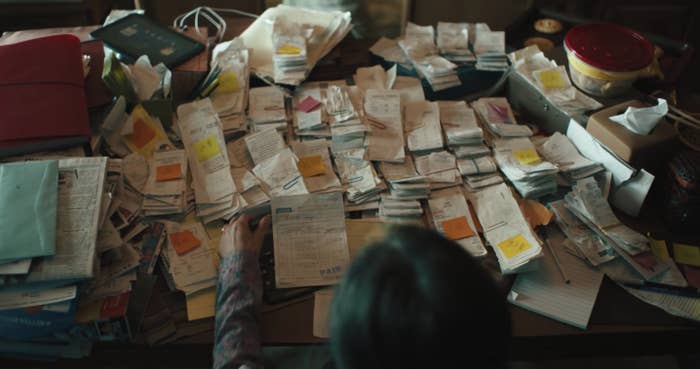 Michelle Yeoh as Evelyn sits at a table with countless receipts to do her taxes