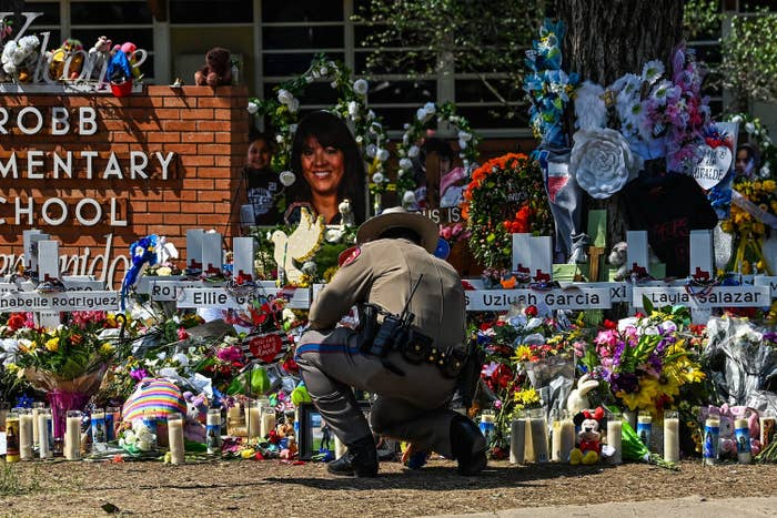 A police officer clears the makeshift memorial before the visit of US President Joe Biden at Robb Elementary School in Uvalde, Texas, on May 29, 2022