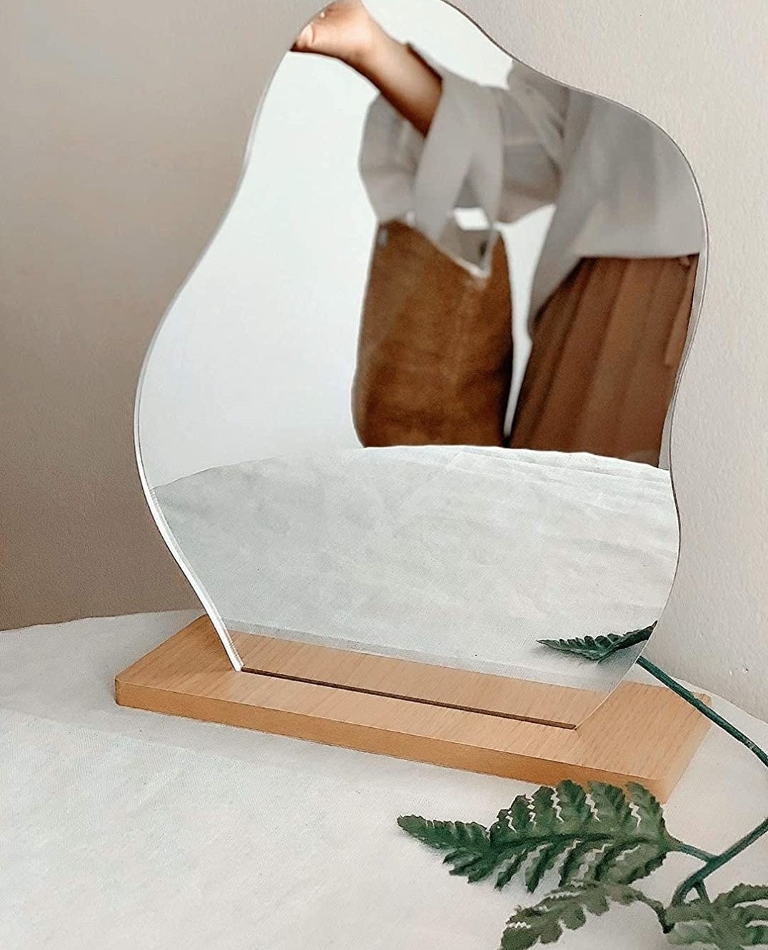 an organic shaped mirror on a wooden mount