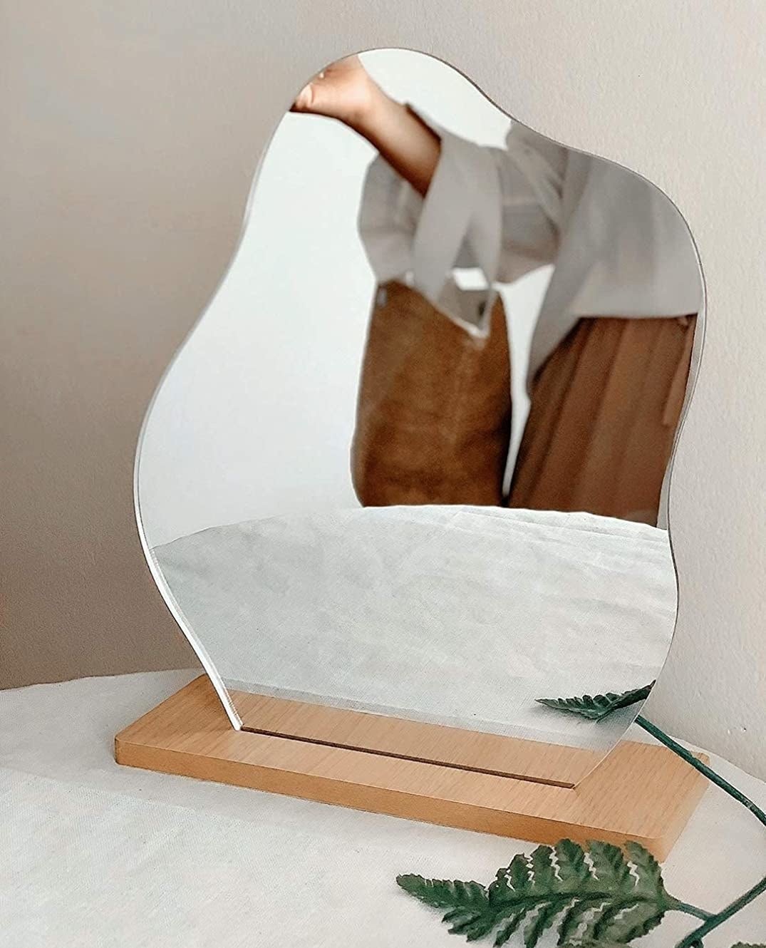 an organic shaped mirror on a wooden mount