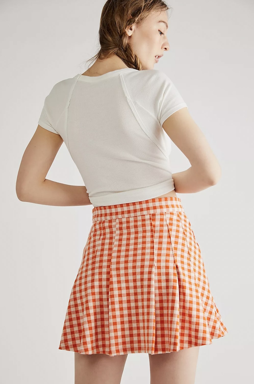 Model from behind in the orange and white plaid skirt with white top