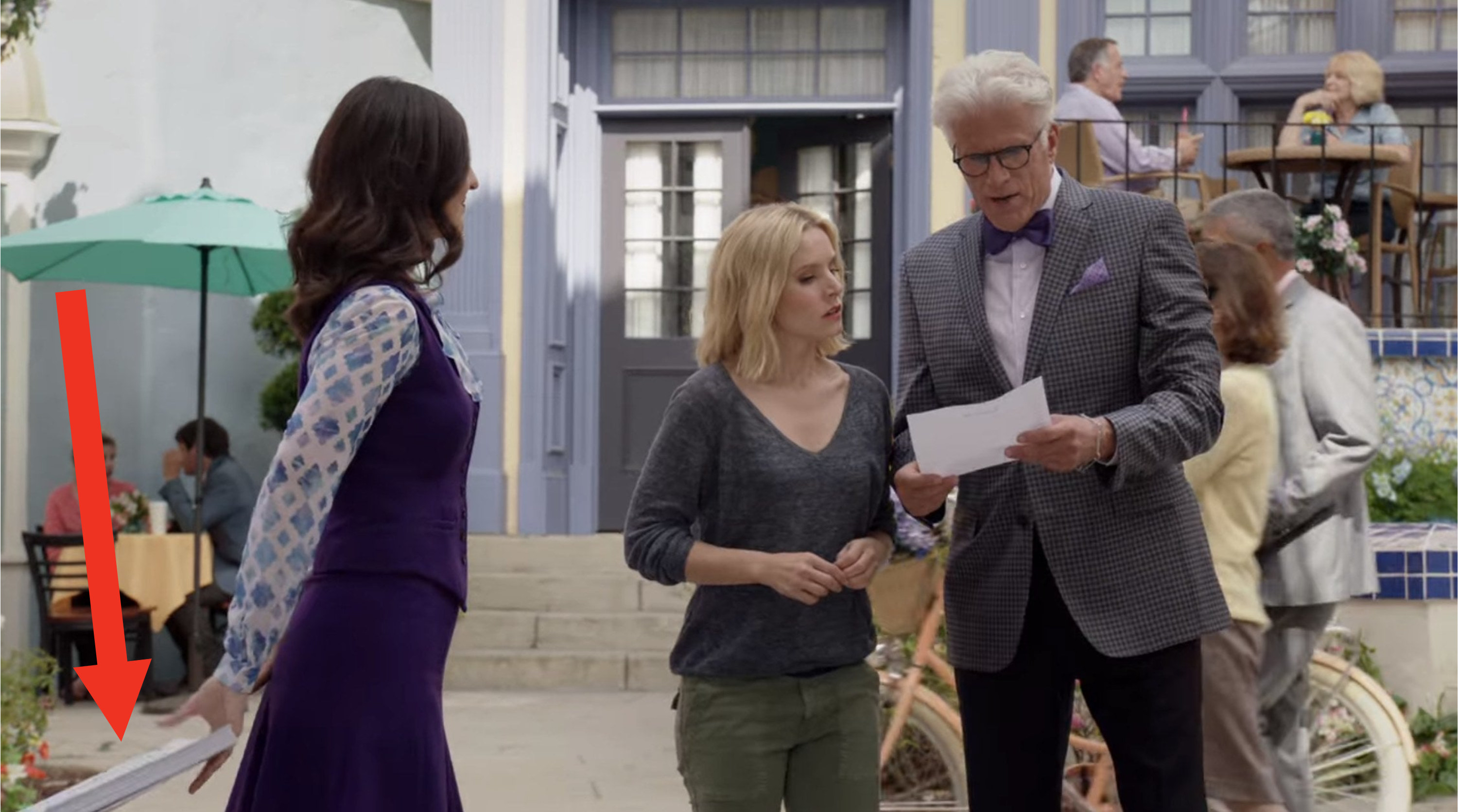 Someone offscreen handing Janet a stack of papers in The Good Place