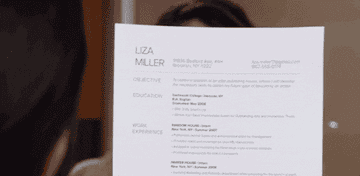 A person smiling in front of an interviewer looking at their resume