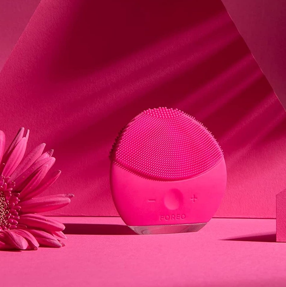 a round facial cleanser next to a flower