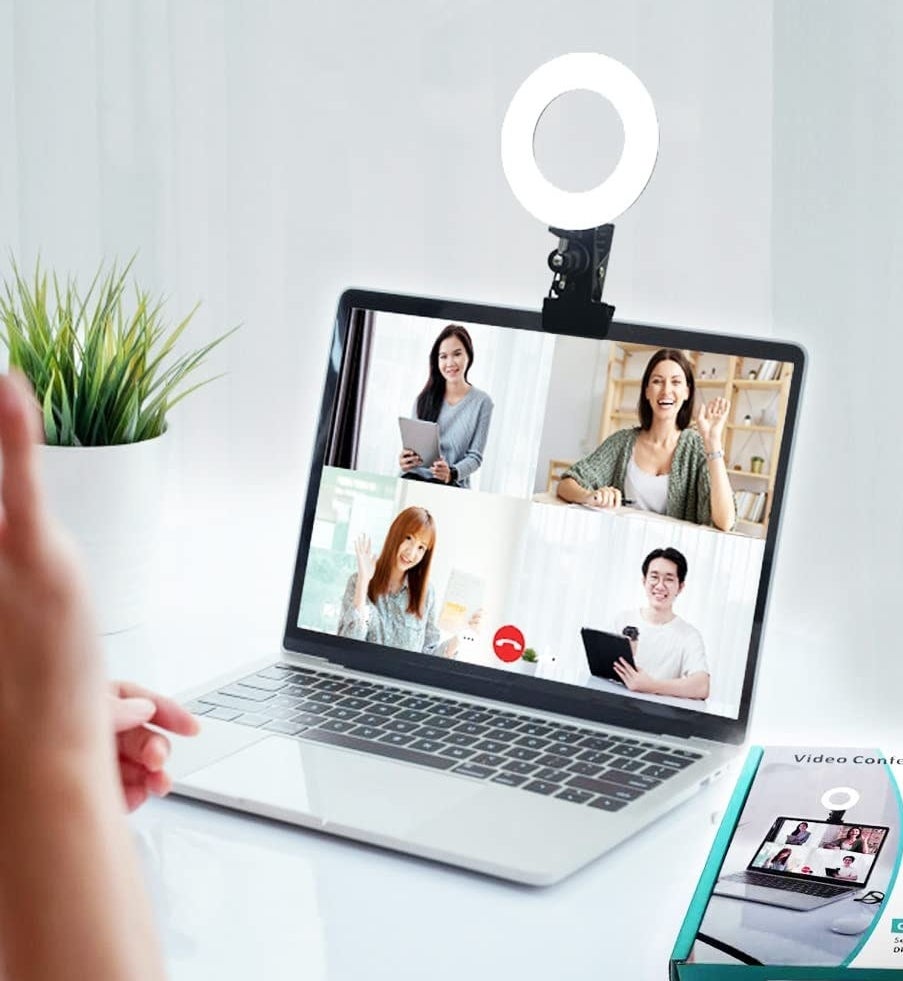 a mini ring light clipped onto the top of a laptop on a white desk
