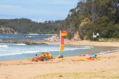 People sitting on a beach near flags