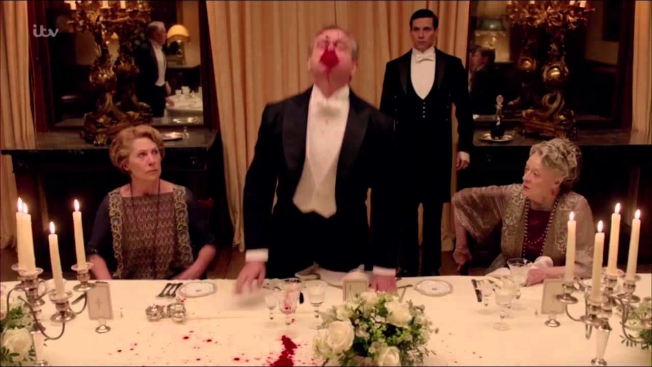 dinner table with a man standing and blood coming from his mouth
