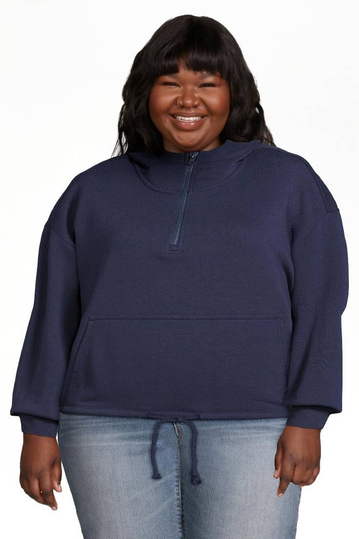 Model wearing blue half-zip sweatshirt with jeans