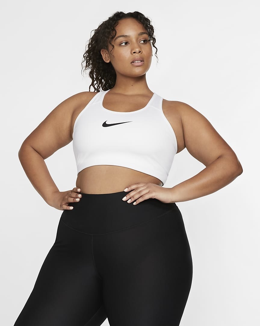 model in a white sports bra with a large black nike swoosh in the center