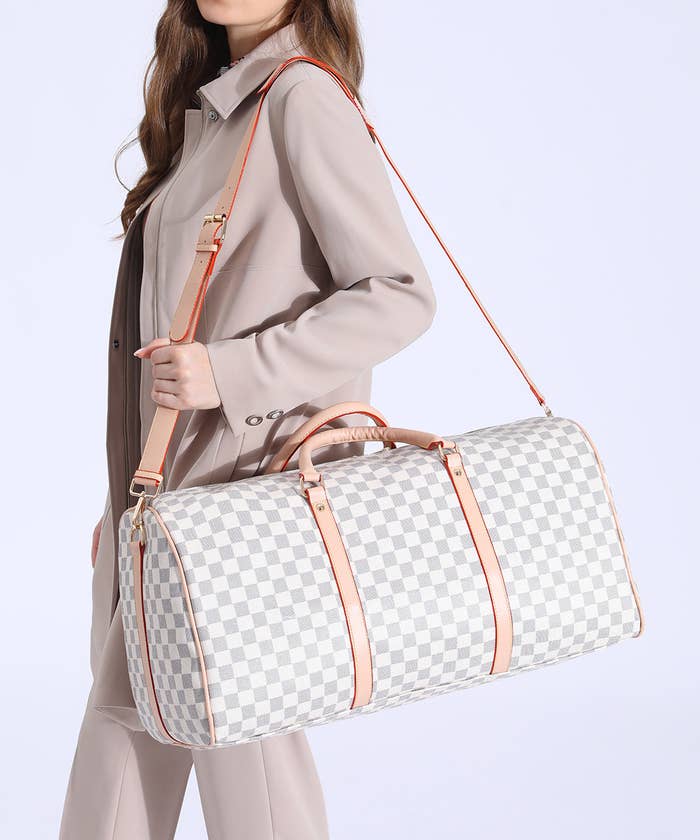 An image of a model carrying a white faux leather checkered duffle bag