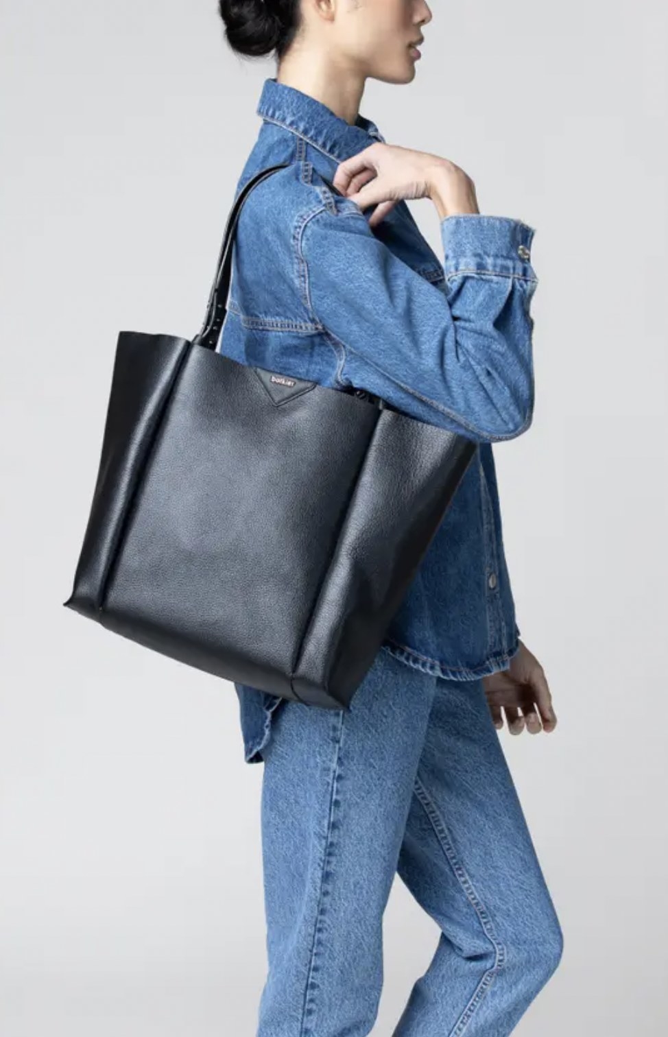 Model with the black leather tote over their shoulder