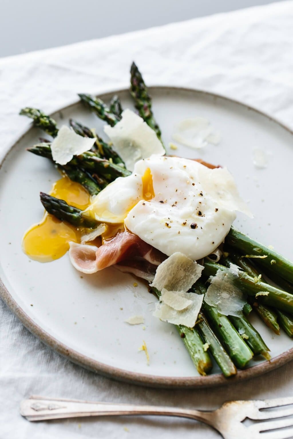 Asparagus topped with cured meat and poached egg.