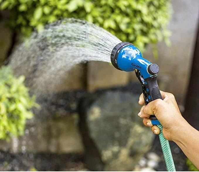 A person watering plants with the shower function on a spray nozzle