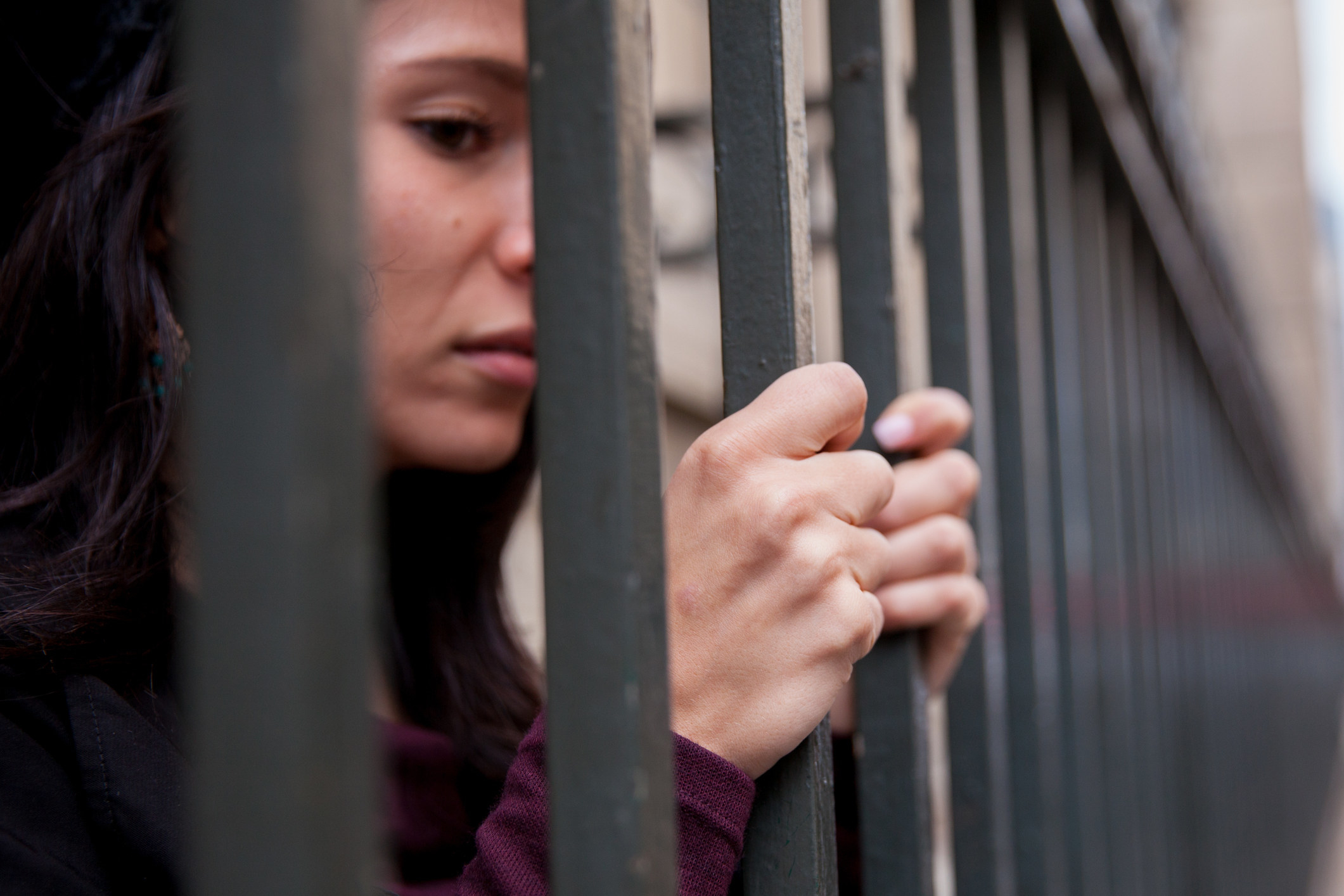 A woman looking sad behind bars